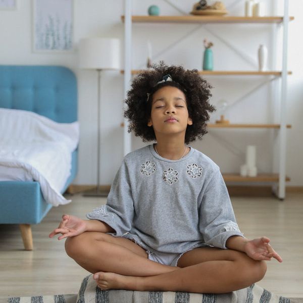 Child maintaining a balanced yoga pose with focus and a calm expression.