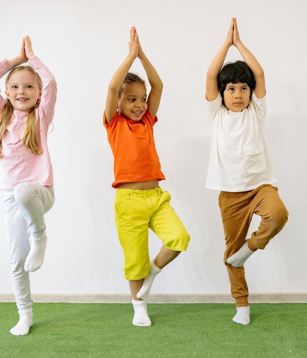 Happy child in a simple yoga pose in a bright room.